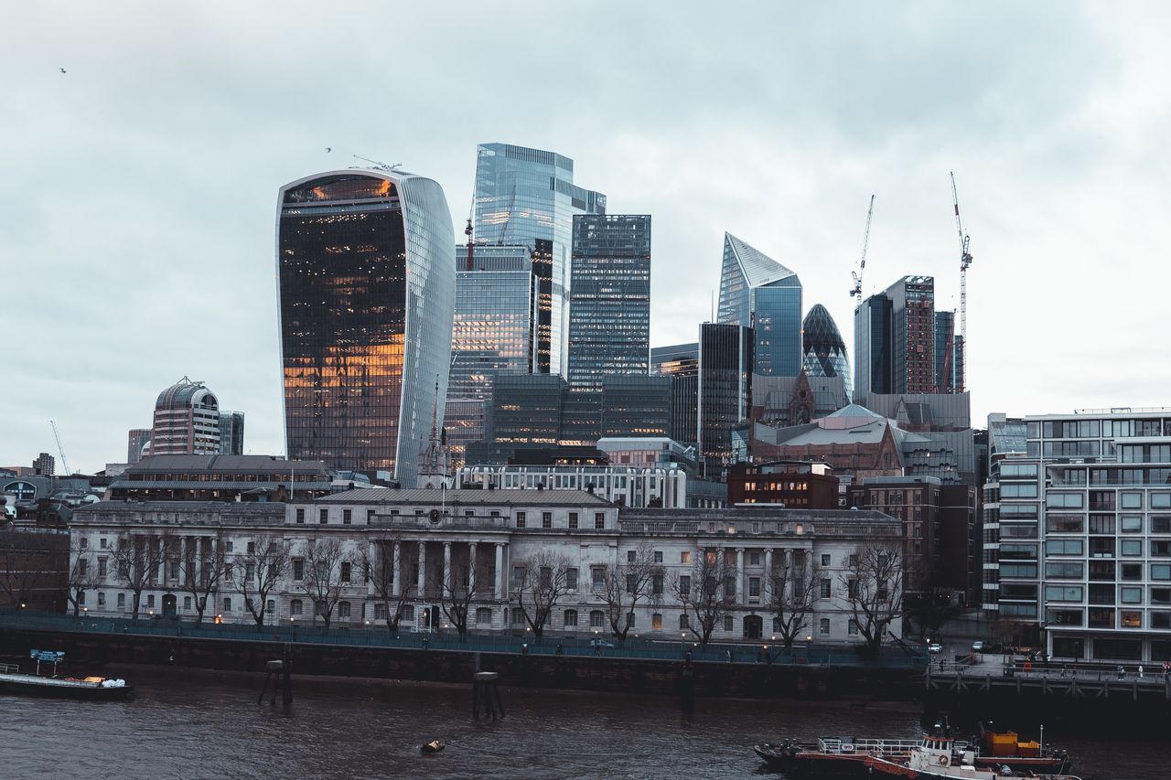 Dramatic view of London's modern skyscrapers with iconic architecture under a cloudy sky.
