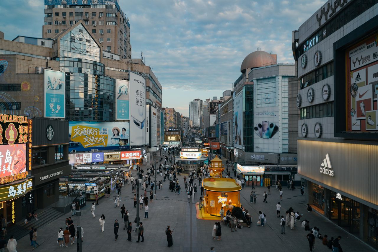High-angle view of a crowded urban shopping district with illuminated advertisements and diverse architecture.