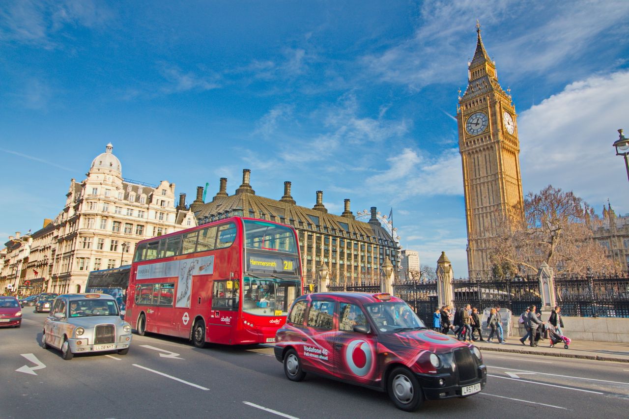 A vibrant scene of London with buses, taxis, and iconic Big Ben amidst urban life.