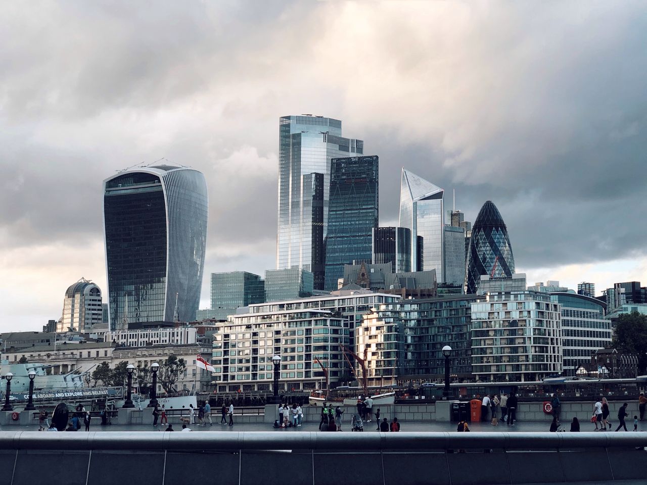 View of London's iconic skyscrapers including The Walkie Talkie and The Gherkin under a cloudy sky.